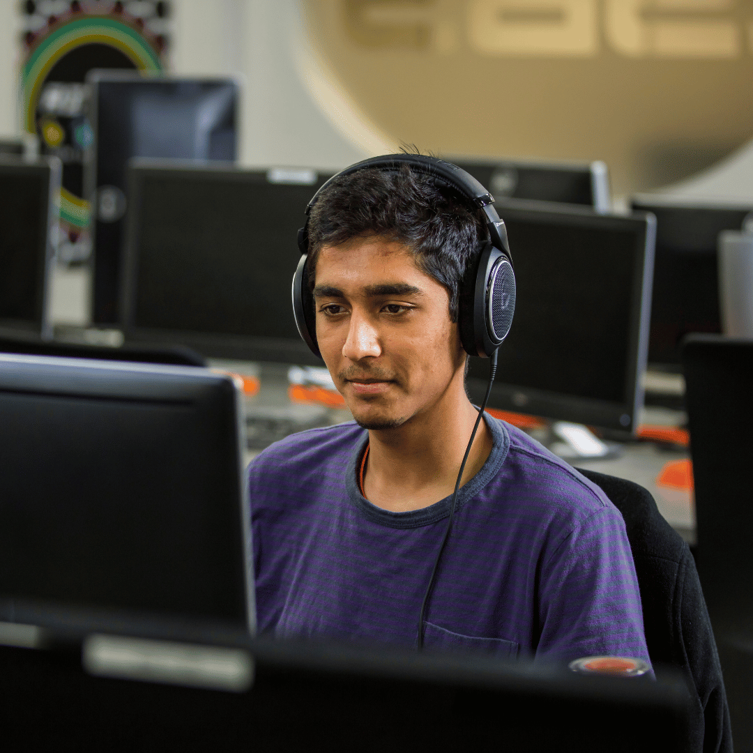 male student at the computer wearing headphones