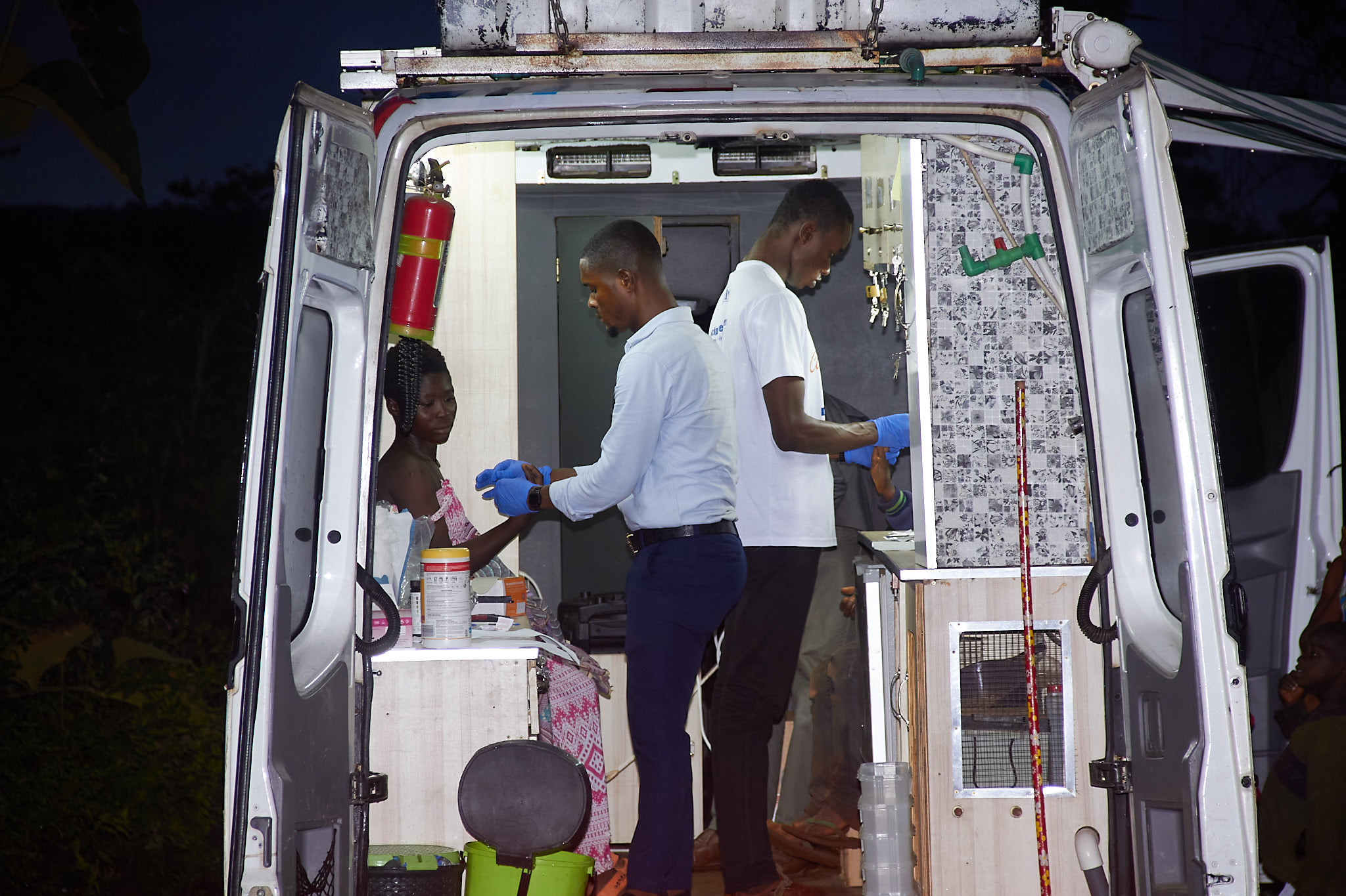 Two men in a van assisting individuals with medical devices.